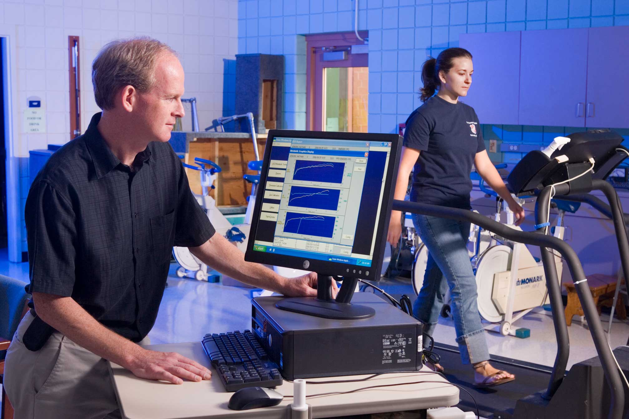 Researcher works with study participant, who is walking on a treadmill