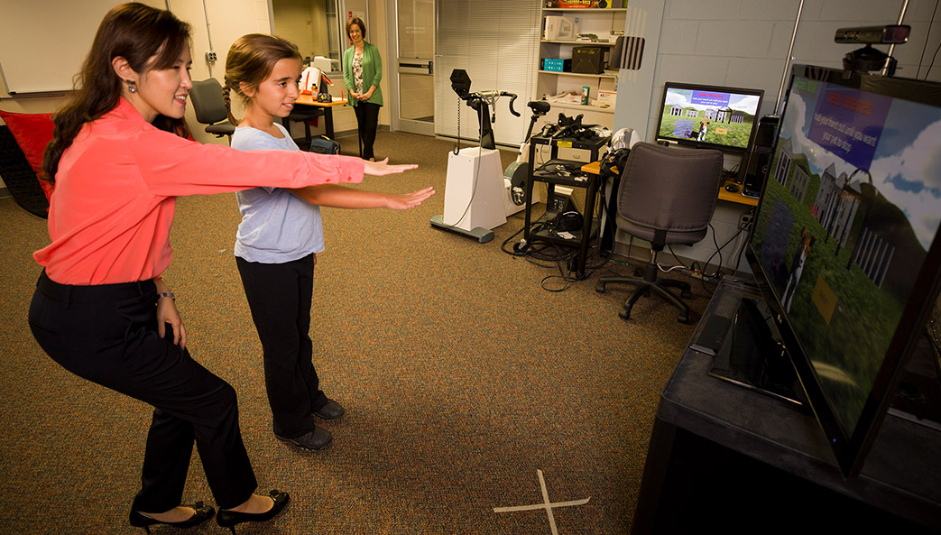 Sun Joo "Grace" Ahn of UGA helps 9-year-old Maddie Lacey interact with the virtual buddy fitness kiosk