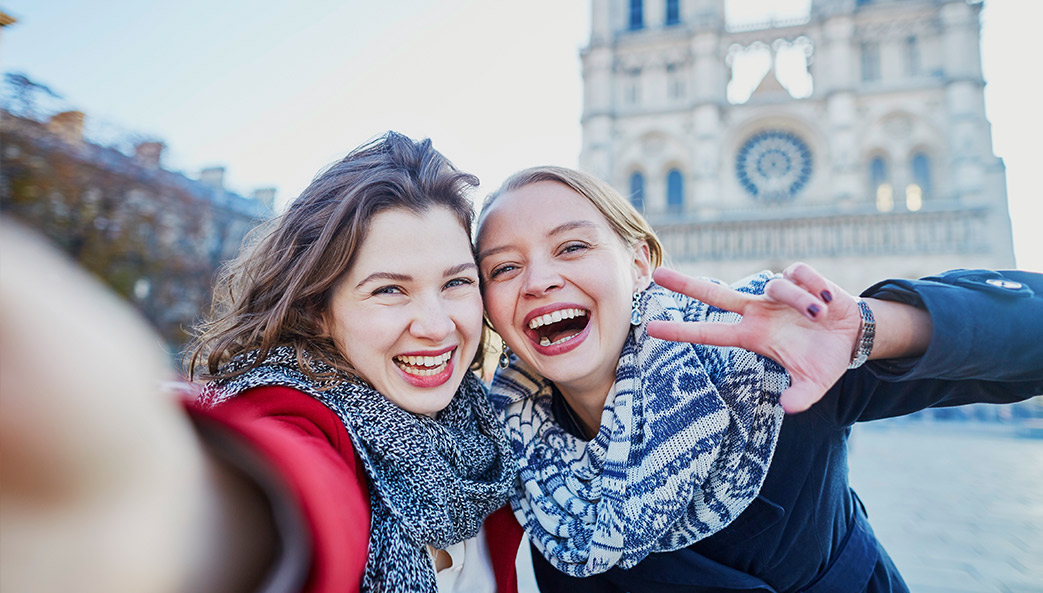 two women taking selfie in front of Notre Dame