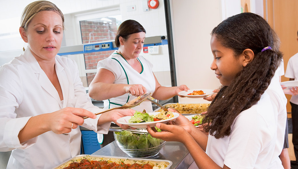 photo of school lunchroom staff serving food to a child