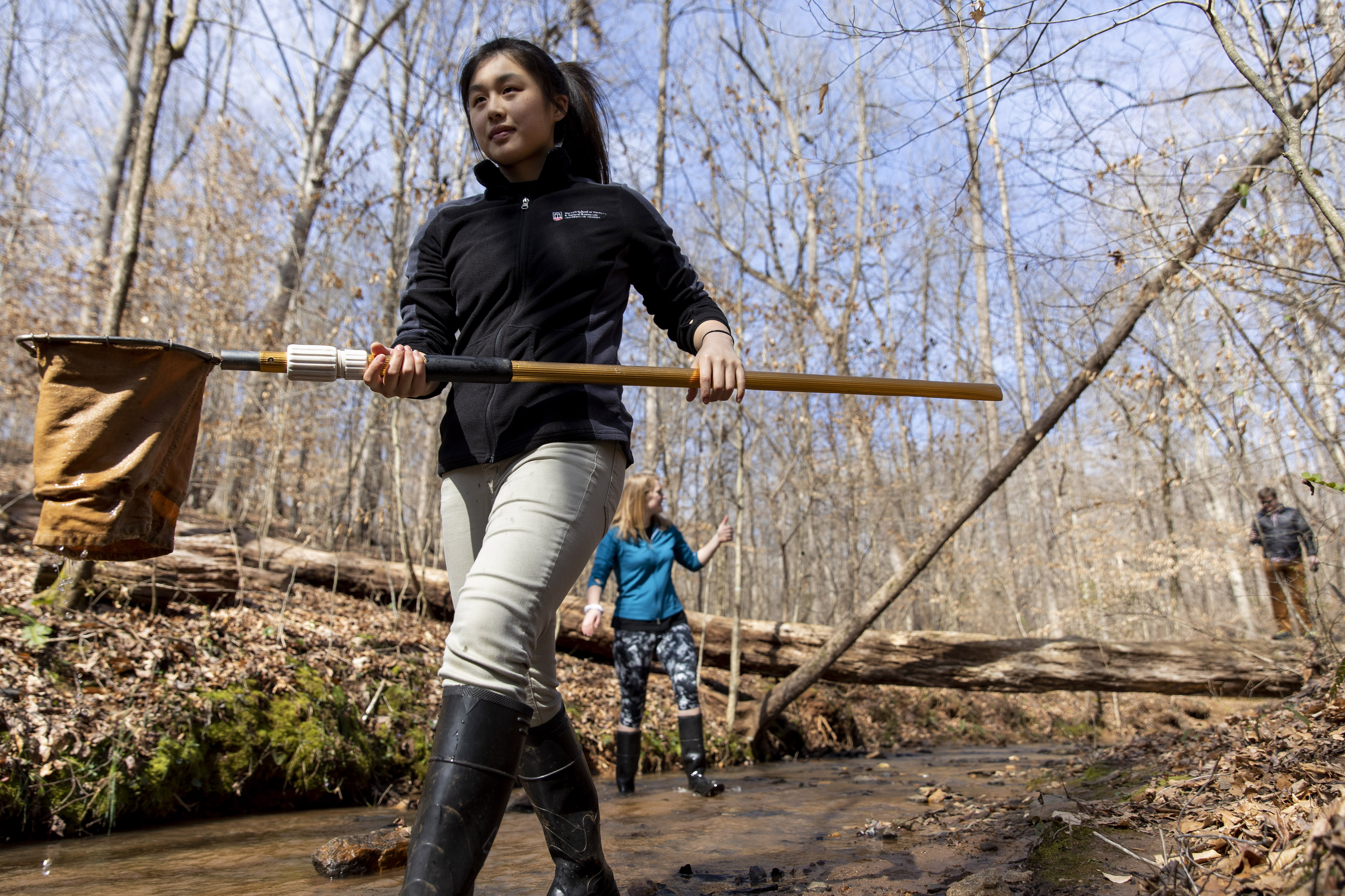 Undergraduate Peyton Niebanck carries a net as she works with her group sampling as part of their Stream Ecology Lab in a stream off the orange trail at the State Botanical Gardens.
