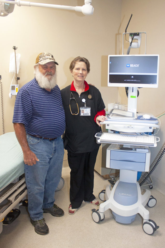 Dennis Hall and Karen Butler, a physician at Emanuel Medical Center in Swainsboro, Ga., stand next to the Remote Evaluation for Acute Ischemic Stroke (REACH) telemedicine cart that played a role in saving Mr. Hall’s life in November 2018. (Photo by Rebecca Ayer)