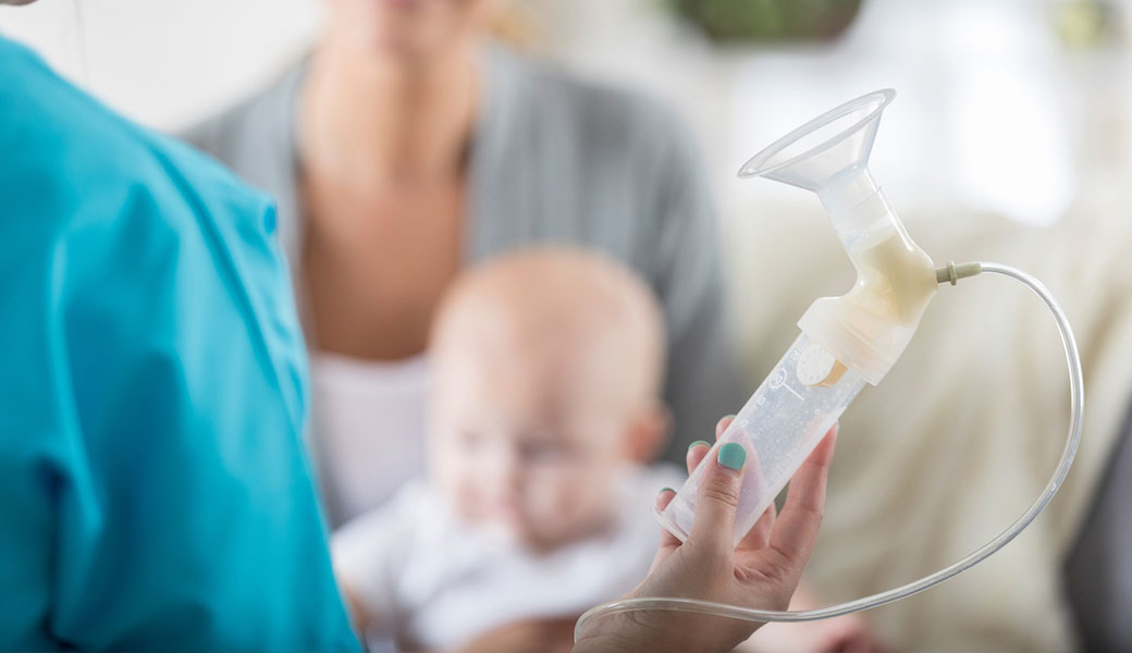 image of mother holding baby and breast pump