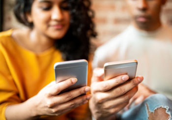 image of two people looking at their cell phones