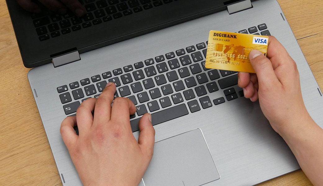 photo of person using credit card to pay on laptop