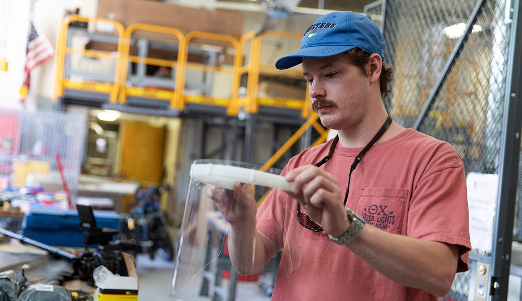 Mechanical engineering undergraduate student and student worker Reames Clark attaches a face shield to a bracket for the shield in UGA's Digital Fabrication Lab on April 3, 2020.