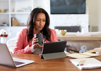 woman drinking from mug while teleworking