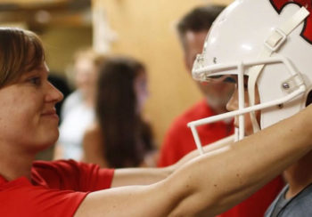 Photo of Julian Schmidt putting a helmet on young boy