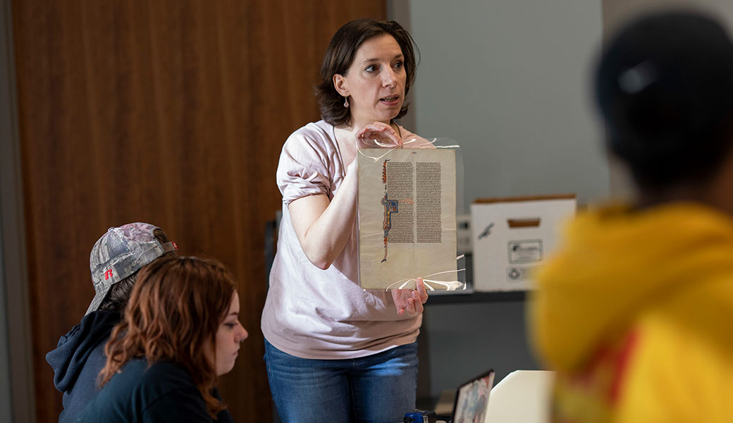 photo of English Professor Cynthia Camp holds up a manuscript in her Manuscripts Class at the Special Collections Libraries