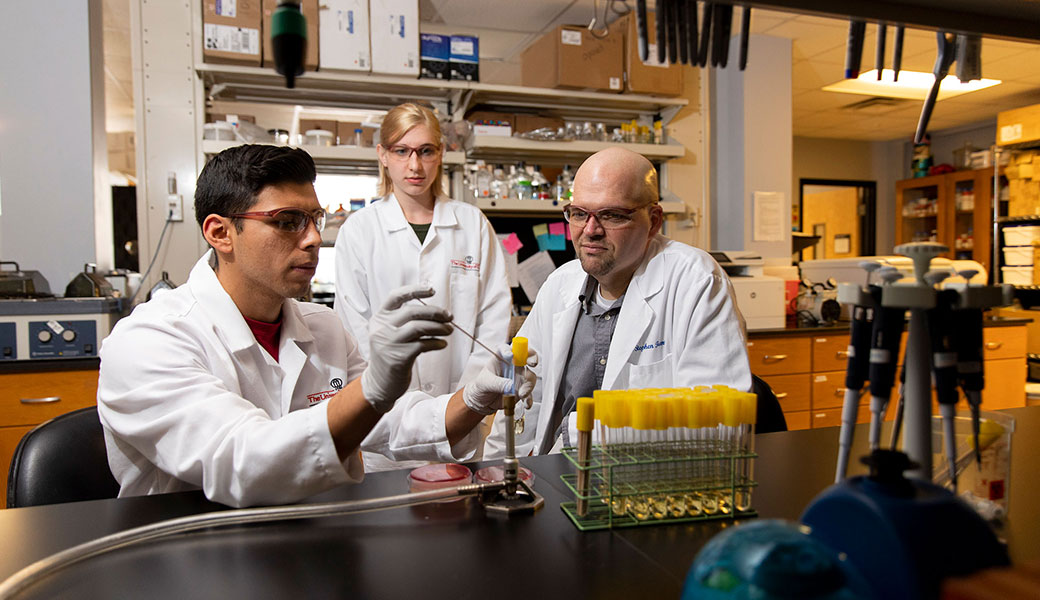 Graduate students (from left) Martin Douglass and Alexandria Purcell work in the laboratory with professor Stephen Trent in 2019