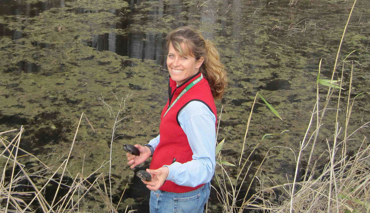 University of Georgia researcher Tracey Tuberville near edge of pond with two turtles