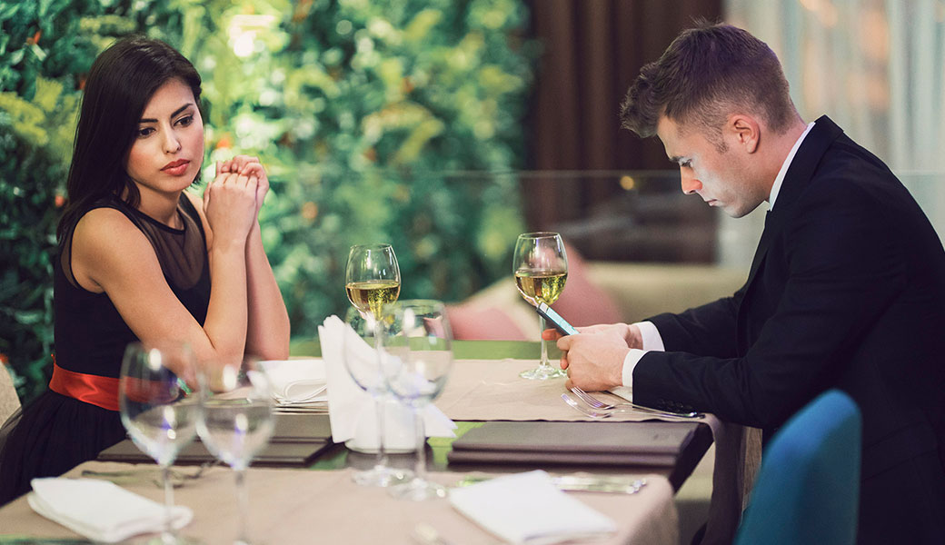 image of man texting at dinner while companion looks on