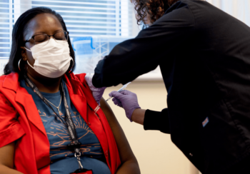 Staff member Nekesha Murphy (left) gets her COVID-19 vaccine from RN Ginn Holder at the University Health Center.