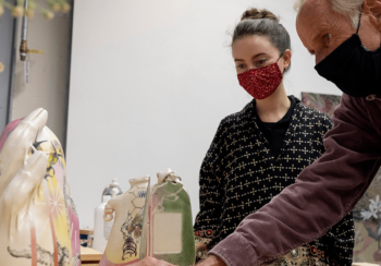 Graduate student Isys Hennigar, left, discusses her ceramic work withTed Saupe, professor of art.