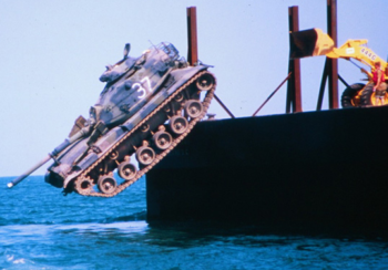 A battle tank is pushed into the ocean to form part of an artificial reef.