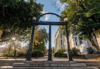 uga gate in front of a building surrounded trees