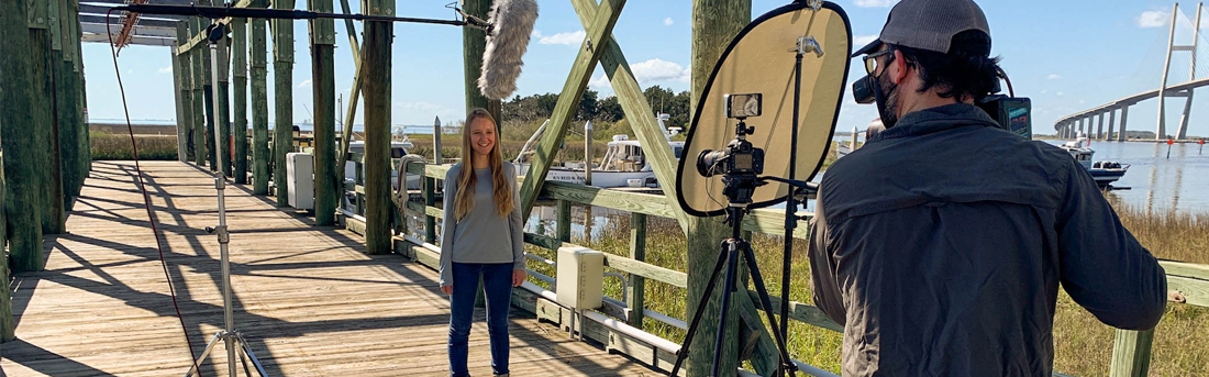 Woman standing on a dock making a video