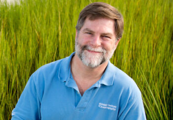 Man smiling standing in a field of tall grass