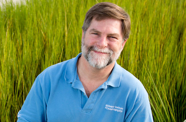 Man smiling standing in a field of tall grass