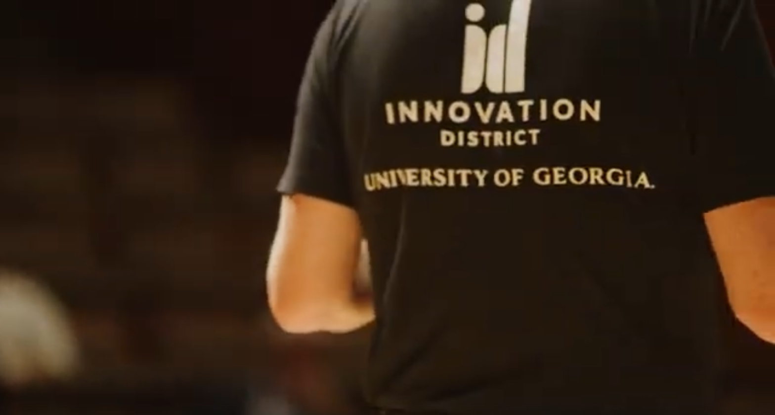 Back of a person with a shirt that reads Innovation District University of Georgia on it