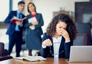 woman sitting at desk pinching her eyes due to stress