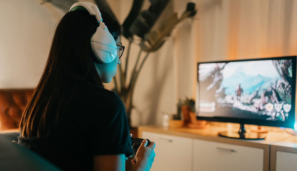 Young female playing video games with a headset on her head.