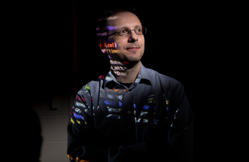 Environmental portrait of School of Computing Professor Roberto Perdisci with computer display projected onto his body.