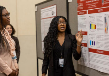 Tolulope Adedipe, left, listening to student researcher Akinniyi explain her CURO project.