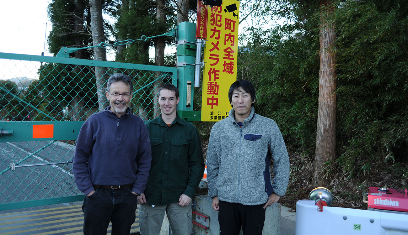 From left: Tom Hinton, Jim Beasley, and Kei Okuda stand outside the nuclear exclusion zone gate in Fukushima, Japan.