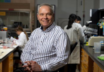 Aaron Mitchell in a Davison Life Sciences Complex laboratory with graduate students working in the background. (Photo by Andrew Davis Tucker/UGA)