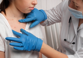 Doctor viewing a patient with red bumps on her skin from a measles outbreak.