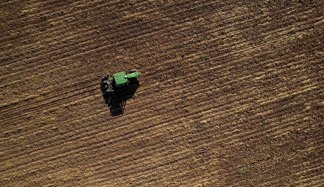 Green Tractor harvesting on a field.