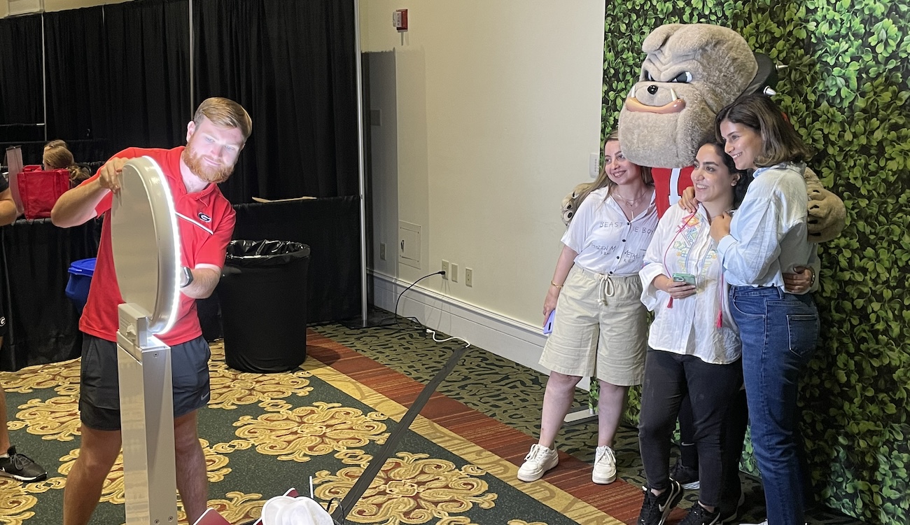 Hairy Dawg takes a picture with three new graduate students