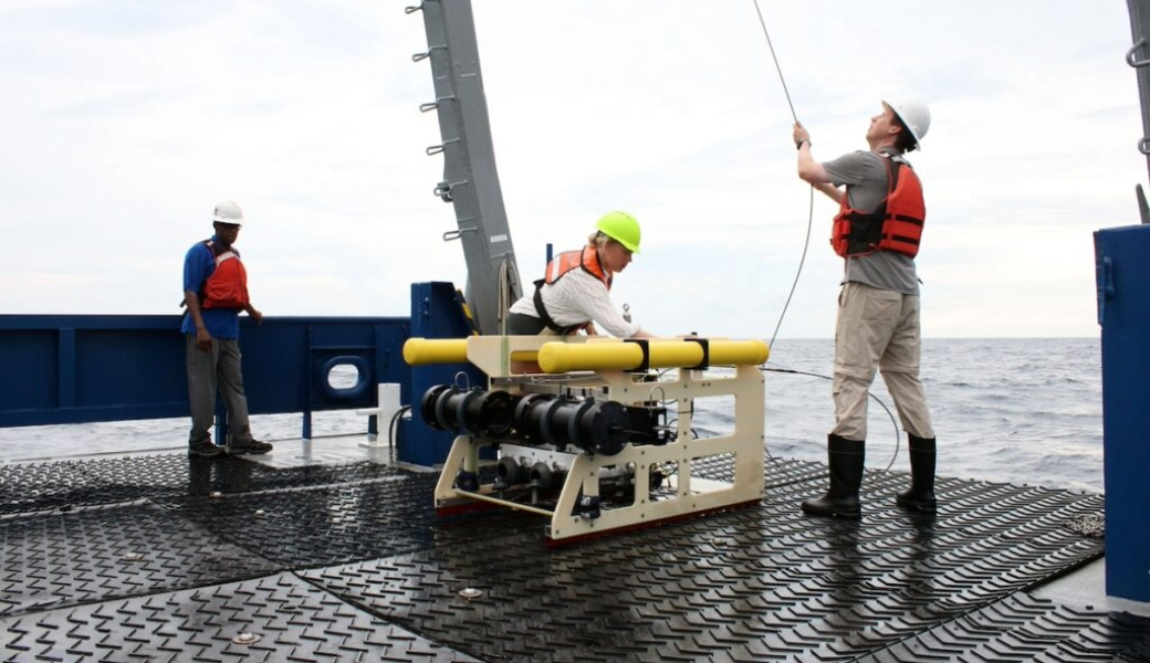 Adam Greer (right) and graduate student Grace Mann prepare the towed plankton imaging instrument aboard the R/V Savannah, as Derrick Dozier-Muhammed, principal of Johnson High School, watches.