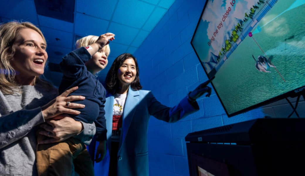 Sun Joo (Grace) Ahn guides Sarah Smith and her son, Boone, through the Virtual Fitness Buddy mixed reality game. (Photo by Chamberlain Smith)