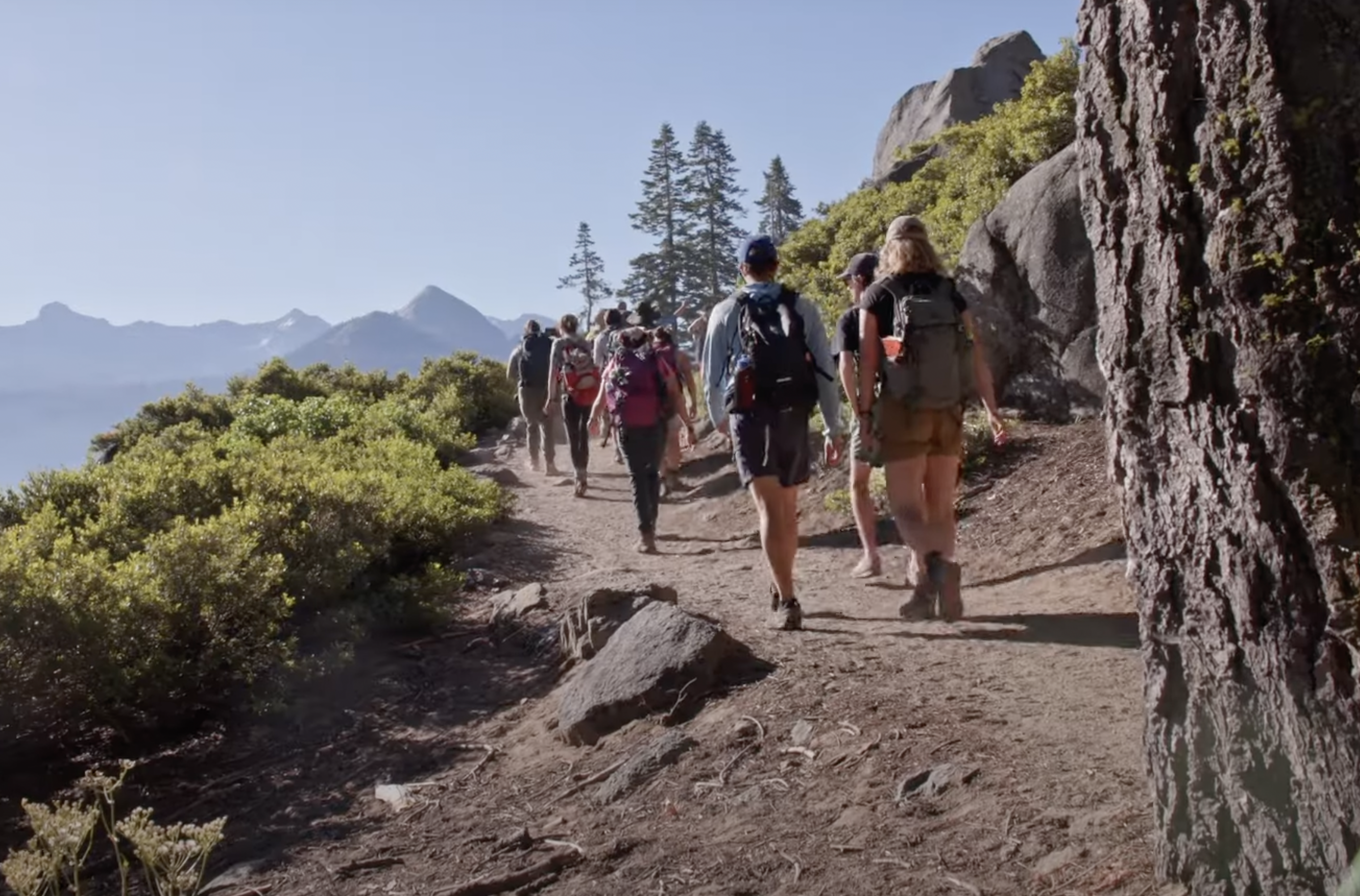 A group of students walks along a path in the mountains.