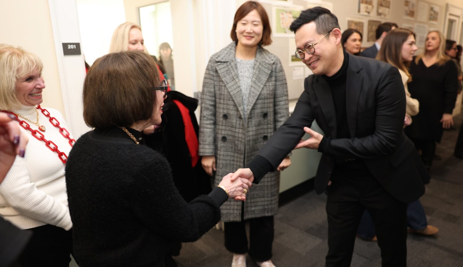 Anne Barge Clegg shakes hands with a smiling man at a reception