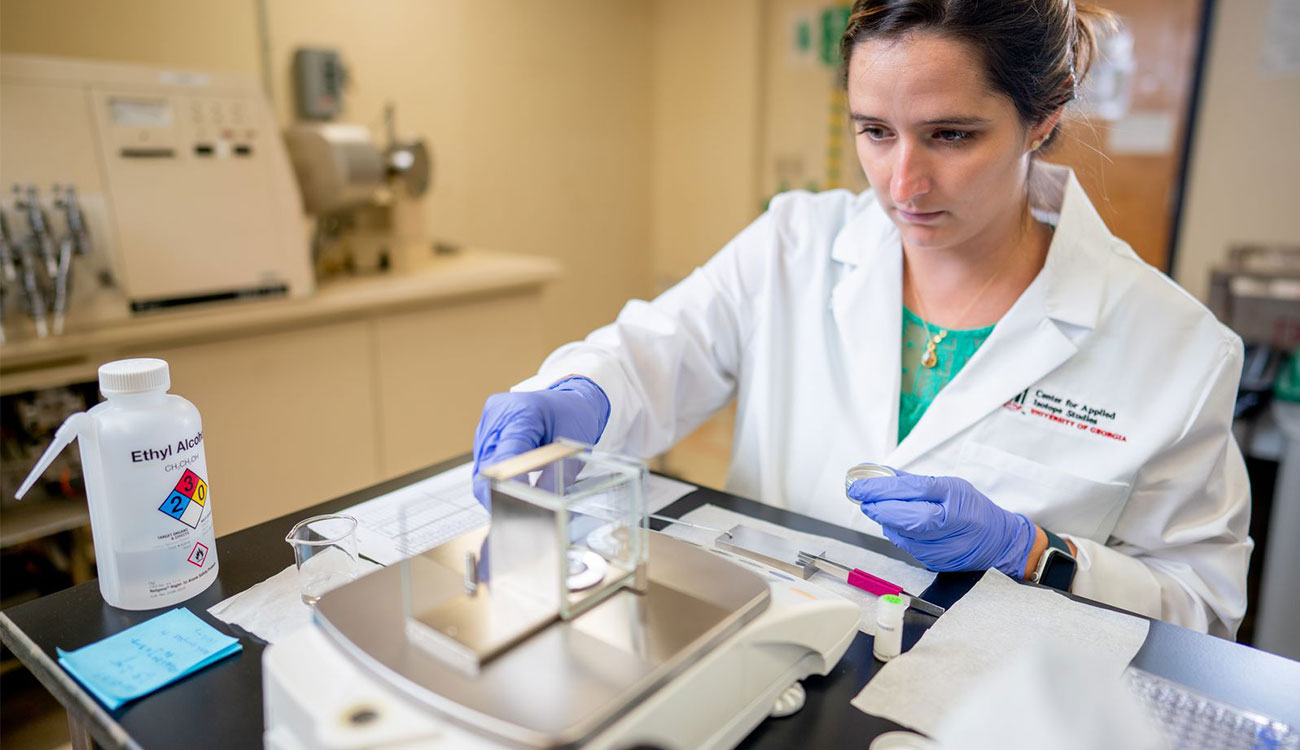 Katie Reinberger weighs cattle teeth samples on a scale at UGA's Center for Applied Isotope Studies.