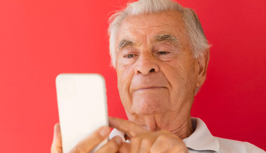 Image of an elderly man using a white mobile phone