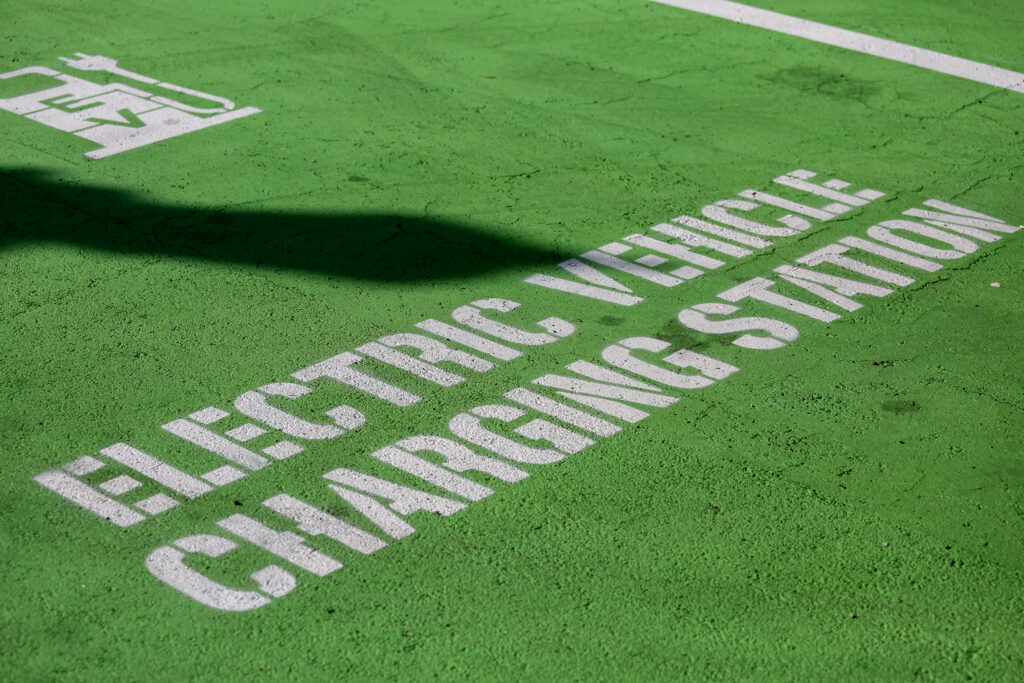 Electric Vehicle charger station painted in green with white text at a parking spot.